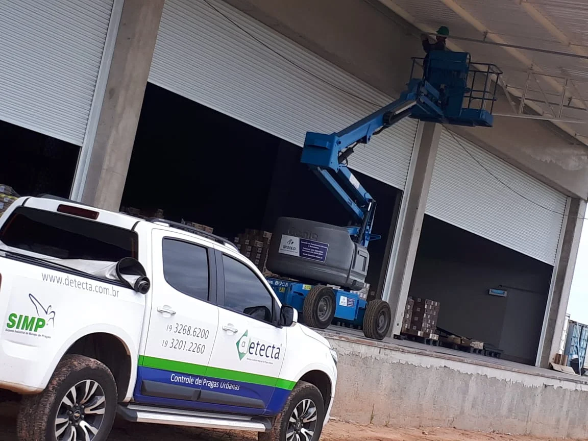 Técnico da Detecta em plataforma elevatória instalando barreiras contra pombos na doca de um galpão