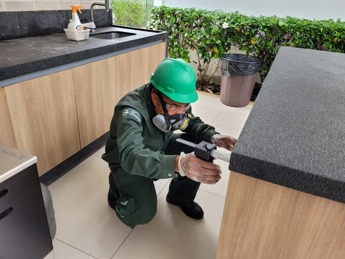 Técnico da Detecta aplicando gel inseticida em uma cozinha